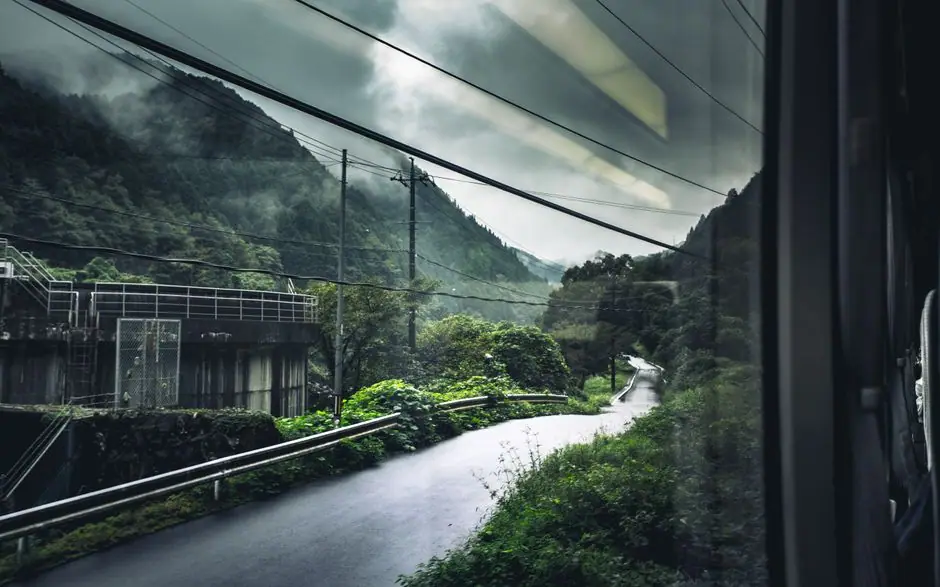 列車の窓から見える雨の山あいの風景